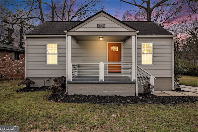 bungalow with covered porch and a lawn