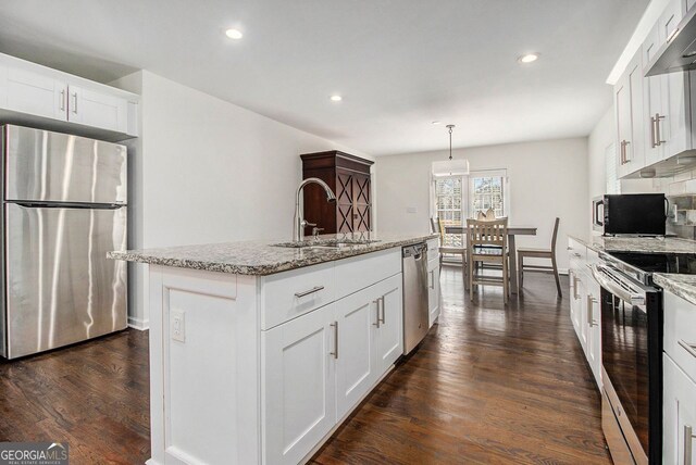 kitchen with pendant lighting, sink, appliances with stainless steel finishes, a kitchen island with sink, and white cabinetry