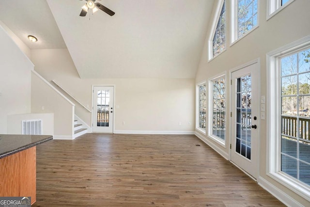 unfurnished living room with dark wood-type flooring, high vaulted ceiling, and ceiling fan