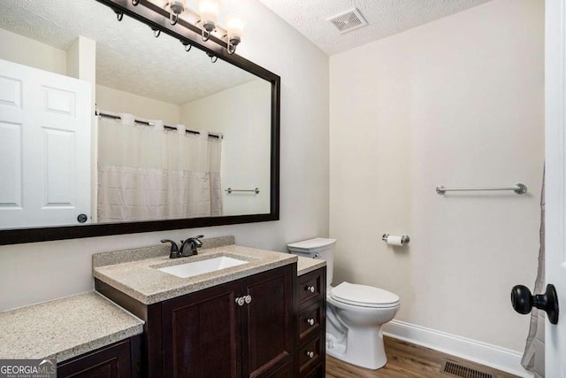 bathroom featuring vanity, hardwood / wood-style floors, a textured ceiling, and toilet