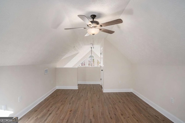 bonus room featuring hardwood / wood-style flooring, ceiling fan, lofted ceiling, and a textured ceiling