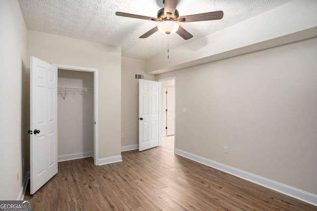 unfurnished bedroom with hardwood / wood-style flooring, ceiling fan, a textured ceiling, and a closet