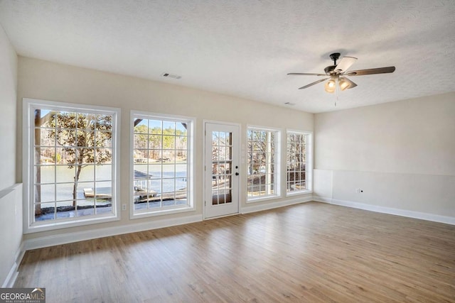 spare room with hardwood / wood-style floors, a wealth of natural light, and a textured ceiling