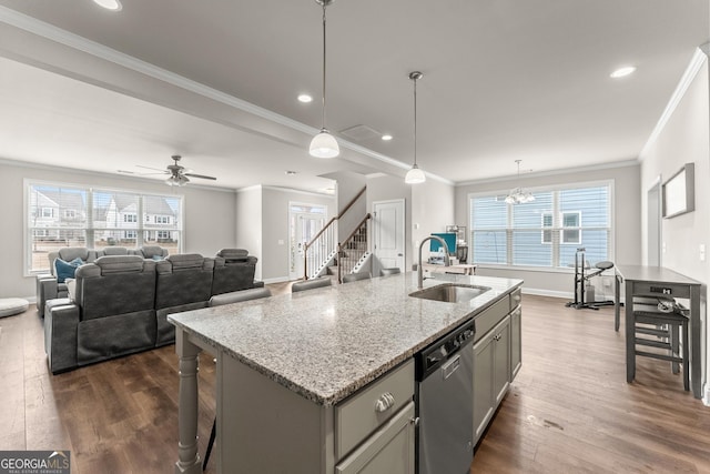 kitchen with dark hardwood / wood-style floors, an island with sink, sink, stainless steel dishwasher, and light stone countertops