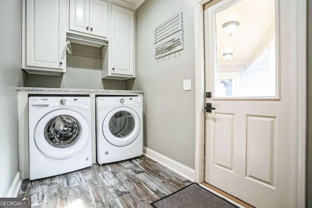 clothes washing area with cabinets, wood-type flooring, and washing machine and dryer