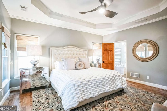 bedroom featuring ornamental molding, hardwood / wood-style floors, and a tray ceiling