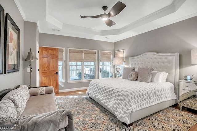 bedroom featuring ornamental molding, hardwood / wood-style floors, ceiling fan, and a tray ceiling