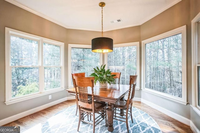 dining area with crown molding and light hardwood / wood-style flooring