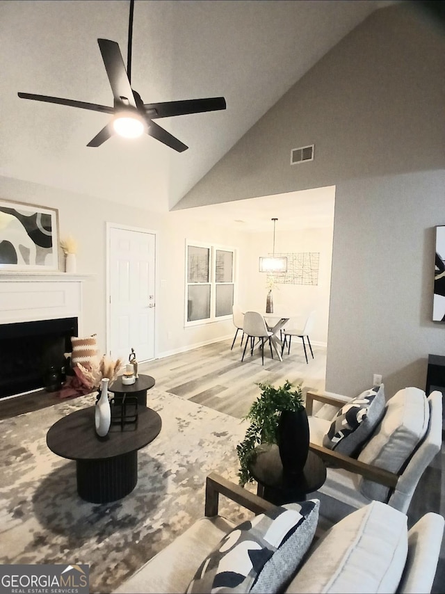 living room with ceiling fan, high vaulted ceiling, and light hardwood / wood-style flooring