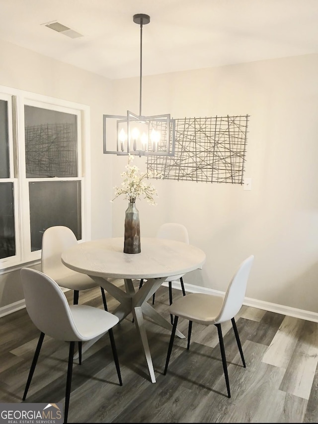 dining space featuring hardwood / wood-style flooring and a notable chandelier