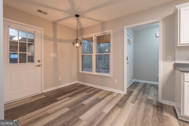 unfurnished dining area with hardwood / wood-style flooring and a chandelier