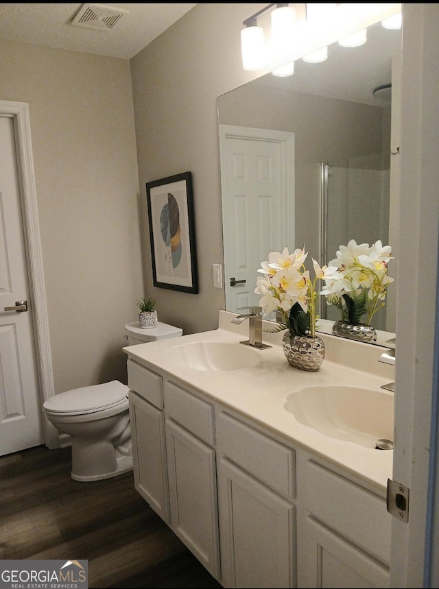 bathroom featuring vanity, wood-type flooring, toilet, and walk in shower