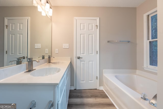 bathroom featuring hardwood / wood-style flooring, vanity, a textured ceiling, and a tub to relax in