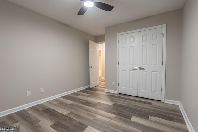 unfurnished bedroom featuring hardwood / wood-style floors, a closet, and ceiling fan