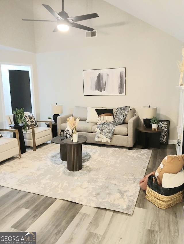 living room featuring hardwood / wood-style flooring, ceiling fan, and high vaulted ceiling