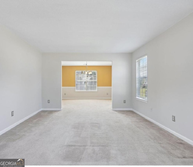 spare room with an inviting chandelier and light colored carpet