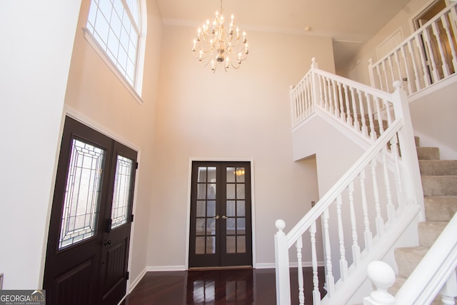 entryway featuring dark hardwood / wood-style flooring, a towering ceiling, french doors, and a chandelier