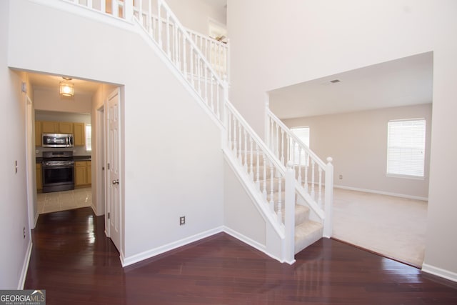 staircase with wood-type flooring and a high ceiling