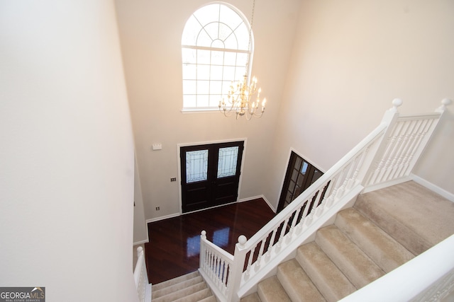 entrance foyer featuring an inviting chandelier, a towering ceiling, and hardwood / wood-style flooring