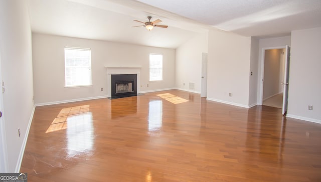 unfurnished living room with hardwood / wood-style floors, a wealth of natural light, ceiling fan, and vaulted ceiling