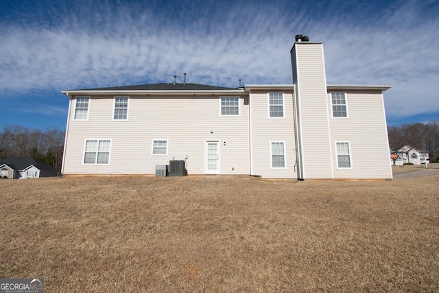 rear view of property with central AC unit and a yard