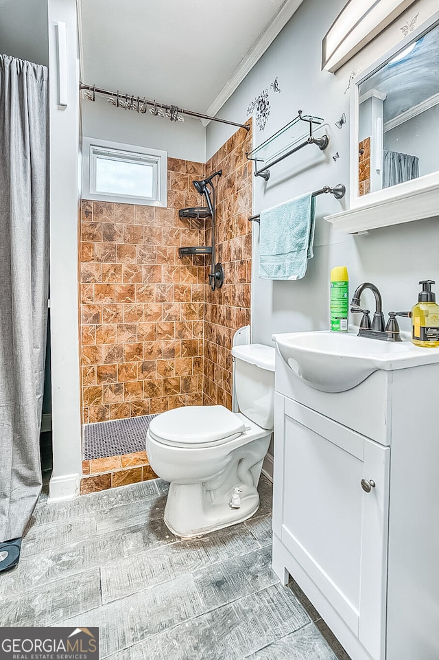 full bathroom featuring vanity, ornamental molding, a tile shower, and toilet