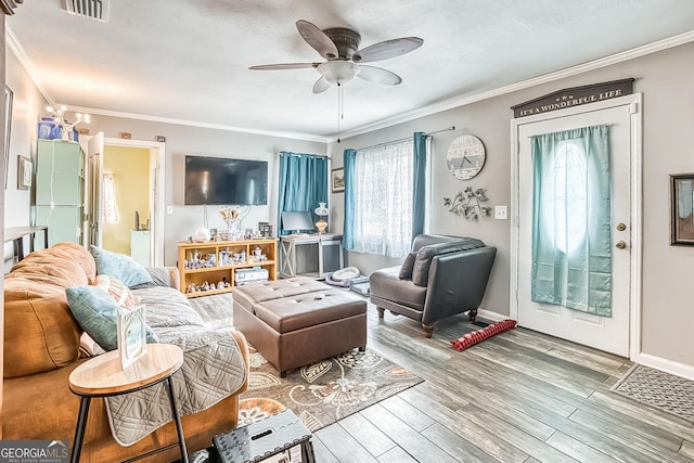 living room featuring ornamental molding, wood finished floors, visible vents, and a ceiling fan