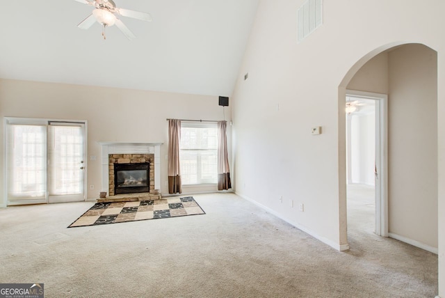 unfurnished living room featuring visible vents, high vaulted ceiling, a ceiling fan, arched walkways, and carpet flooring