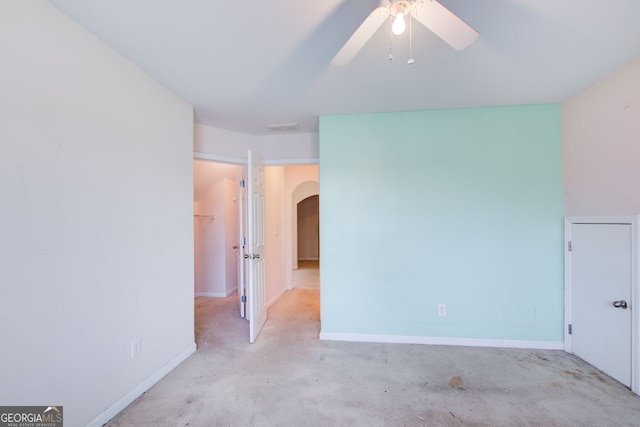 spare room featuring arched walkways, visible vents, ceiling fan, and baseboards