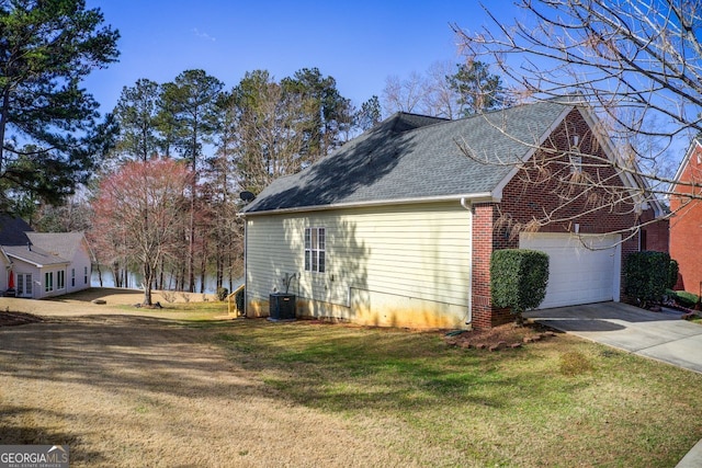 view of side of property with brick siding, central AC, a yard, a garage, and driveway