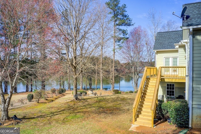 view of yard featuring a deck with water view and stairs