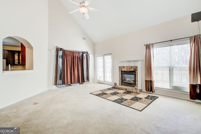 unfurnished living room with visible vents, high vaulted ceiling, a stone fireplace, carpet flooring, and ceiling fan