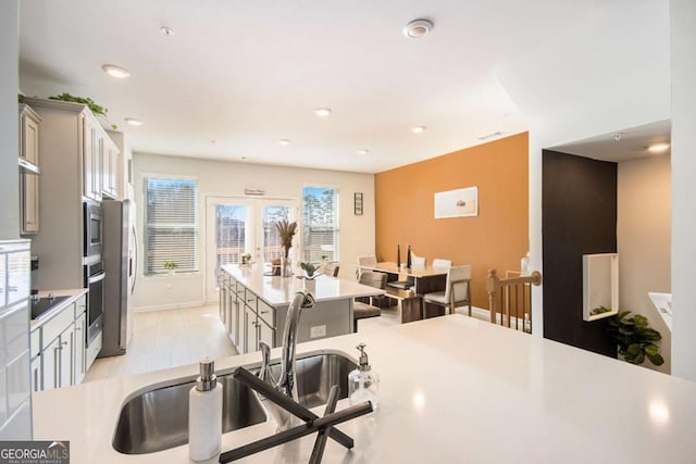 kitchen with a kitchen island, sink, gray cabinetry, stainless steel appliances, and french doors