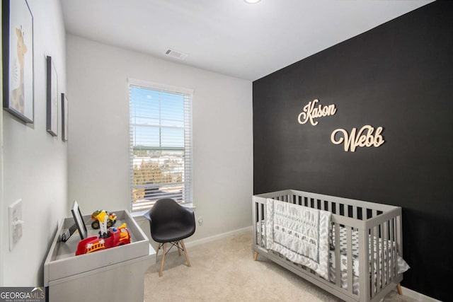 bedroom with light colored carpet and a nursery area