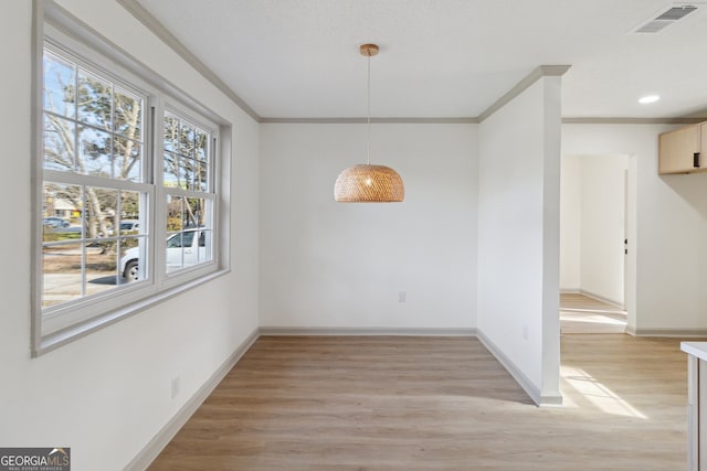 unfurnished dining area featuring ornamental molding and light hardwood / wood-style floors