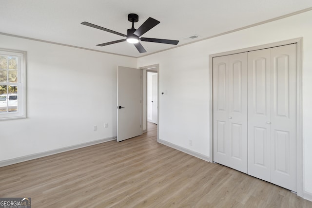 unfurnished bedroom featuring ornamental molding, a closet, ceiling fan, and light wood-type flooring