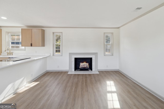 unfurnished living room featuring ornamental molding, a healthy amount of sunlight, and light wood-type flooring