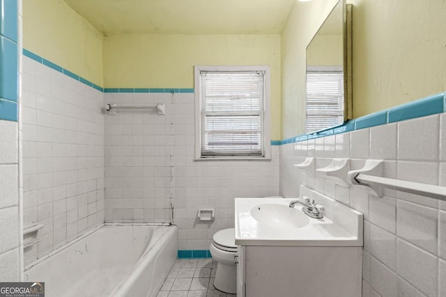 bathroom featuring a washtub, tile walls, vanity, tile patterned floors, and toilet