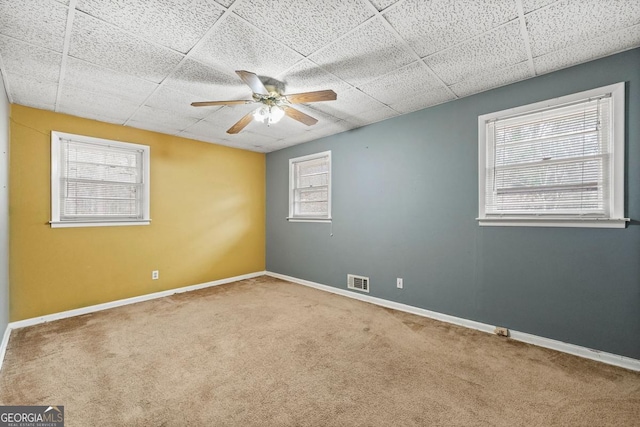 empty room with ceiling fan, carpet flooring, and a drop ceiling