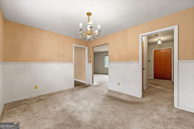 carpeted spare room with a chandelier