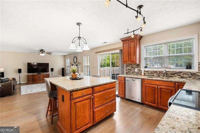 kitchen featuring decorative light fixtures, sink, decorative backsplash, a center island, and stainless steel dishwasher