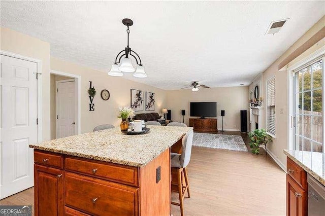 kitchen featuring a kitchen island, pendant lighting, a kitchen bar, and light hardwood / wood-style flooring