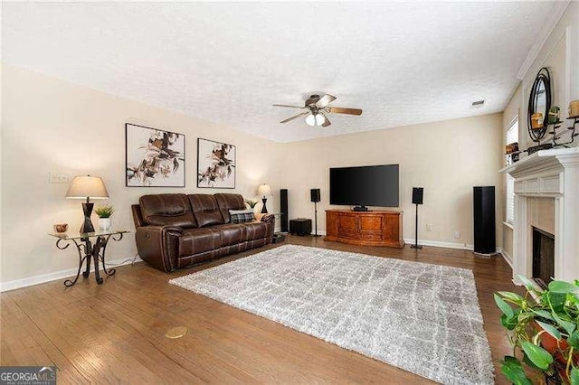 living room featuring ceiling fan, a textured ceiling, and dark hardwood / wood-style flooring