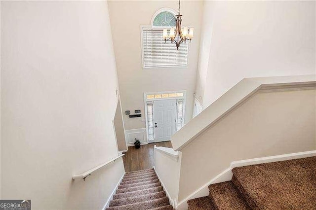 stairs with a towering ceiling and a chandelier