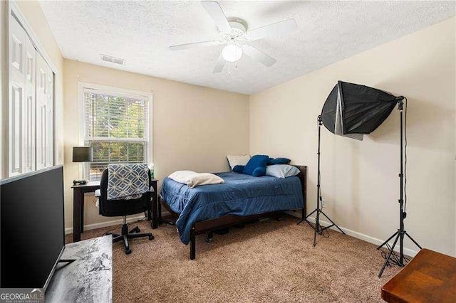 carpeted bedroom with ceiling fan and a textured ceiling