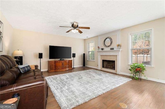 living room with ceiling fan, a textured ceiling, and dark hardwood / wood-style flooring