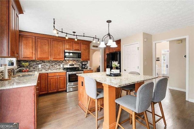 kitchen featuring tasteful backsplash, sink, hanging light fixtures, a center island, and stainless steel appliances