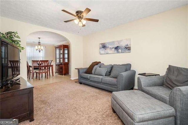 carpeted living room featuring ceiling fan with notable chandelier and a textured ceiling