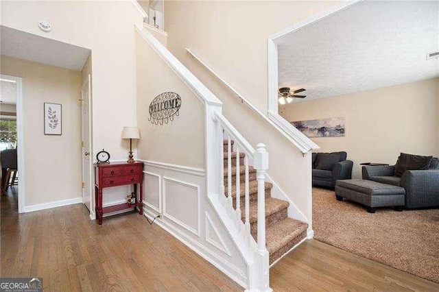 staircase with hardwood / wood-style flooring and ceiling fan