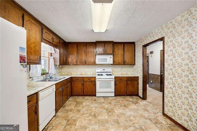 kitchen with white appliances, sink, and a textured ceiling